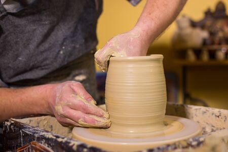 Professional male potter working with clay on potters wheel in workshop, studio. Handmade, art and handicraft conceptの写真素材