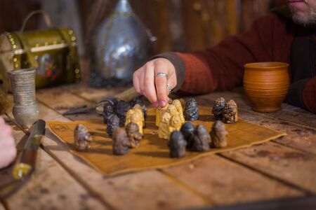 Close up shot - two men in russian ethnic suit playing medieval popular strategy board game - tafl. Folk, competition and traditional conceptの写真素材