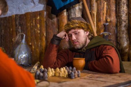 Portrait of man in russian ethnic suit playing board game like chess. Folk, competition and traditional conceptの写真素材
