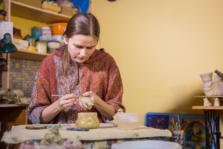 Professional woman potter making ceramic souvenir penny whistle toy bird in pottery workshop, studio. Crafting, artwork and handmade conceptの写真素材