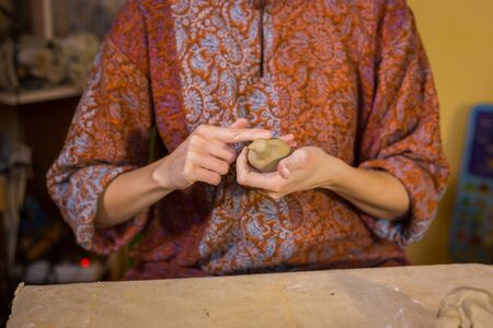 Professional woman potter making ceramic souvenir penny whistle toy bird in pottery workshop, studio. Crafting, artwork and handmade conceptの写真素材