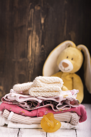 Pile of baby clothes for newborn and funny bunny, selective focusの写真素材
