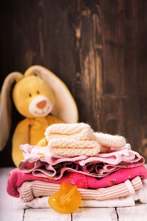 Pile of baby clothes for newborn and funny bunny, selective focusの写真素材