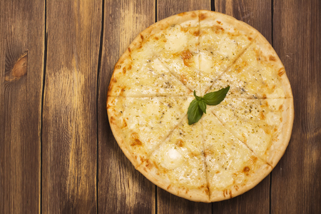 Homemade four cheese pizza with basil and oregano over wooden background. Top viewの写真素材