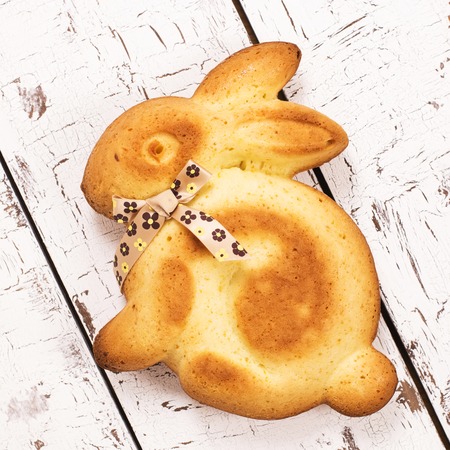 Easter bunny cake with a bow over white wooden tableの写真素材