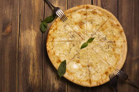 Homemade four cheese pizza with basil and oregano over wooden background. Top viewの写真素材