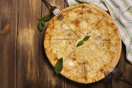 Homemade four cheese pizza with basil and oregano over wooden background. Top viewの写真素材
