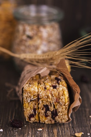 Stack of cereal bars with oat, cranberry, nuts and corn flakes over wooden tableの写真素材