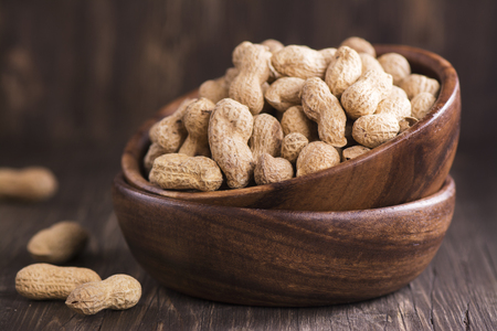 Raw peanuts in wooden bowls over grunge wooden background. Selective focusの写真素材