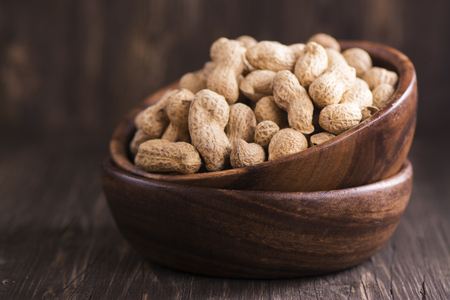 Raw peanuts in wooden bowls over grunge wooden background. Selective focusの写真素材