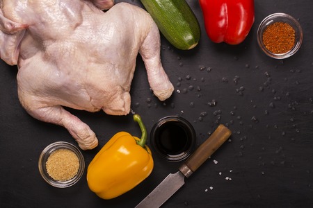 Raw chicken, vegetables and spices over grunge black table. Top viewの写真素材