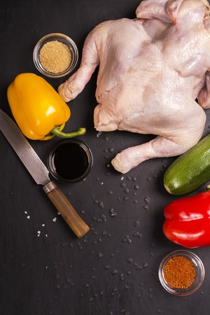 Raw chicken, vegetables and spices over grunge black table. Top viewの写真素材