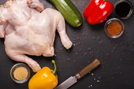 Raw chicken, vegetables and spices over grunge black table. Top viewの写真素材