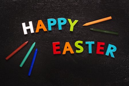 Happy easter greeting card with bright letters and pencils. Toned image. Top viewの写真素材