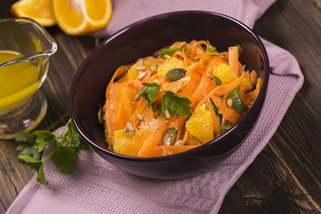Salad with fresh carrot, orange slices, pumpkin and  sunflower seeds. Selective focusの写真素材
