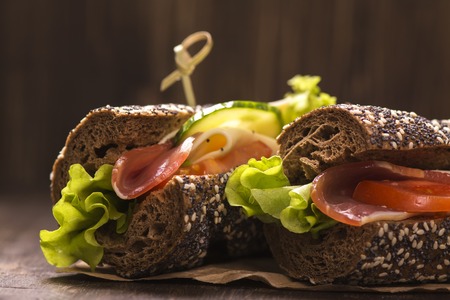 Two healthy sandwiches with ham, cheese and vegetables over grunge wooden tableの写真素材