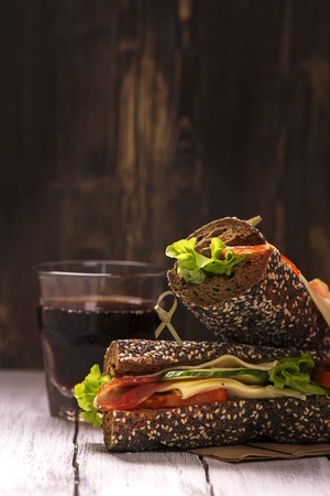 Rye bread sandwiches and glass of cola over wooden background. Selective focusの写真素材