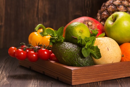 Fresh fruits and vegetables in a wooden tray. Selective focusの写真素材