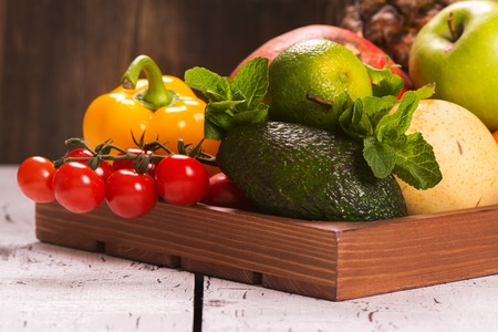 Fresh fruits and vegetables in a wooden tray. Selective focusの写真素材