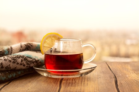 Black tea with lemon slices in a glass cup. View over wet rainy window. Toned image. Selective focusの写真素材