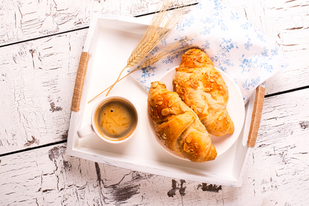 Traditional french breakfast. Crunch croissants and black coffee in a white wooden trayの写真素材
