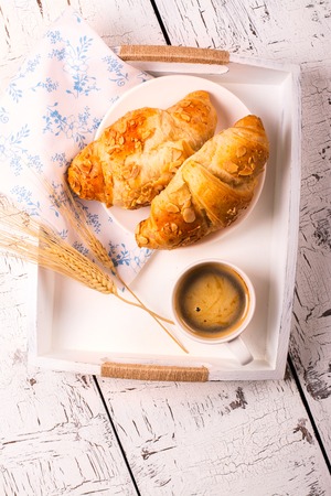 Traditional french breakfast. Crunch croissants and black coffee in a white wooden trayの写真素材
