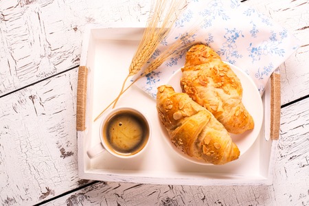 Traditional french breakfast. Crunch croissants and black coffee in a white wooden trayの写真素材