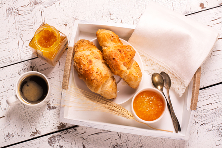 Traditional french breakfast. Crunch croissants and black coffee in a white wooden trayの写真素材