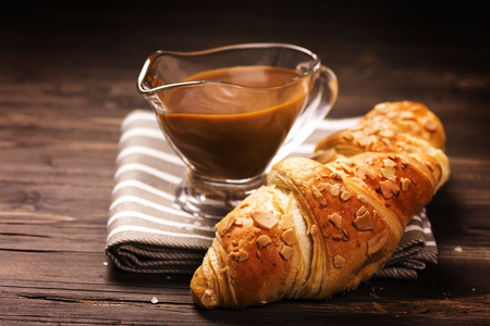 Fresh baked croissants with caramel sauce on wooden table. Toned imageの写真素材