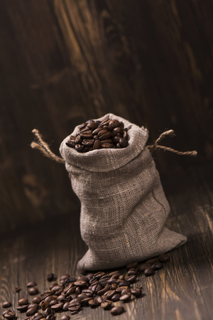 Coffee beans in burlap bags over wooden background. Vintage style. Selective focusの写真素材