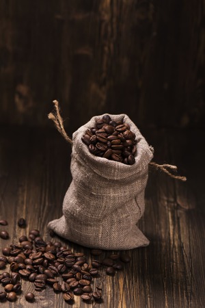 Coffee beans in burlap bags over wooden background. Vintage style. Selective focusの写真素材