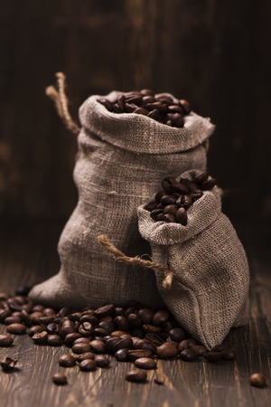 Coffee beans in burlap bags over wooden background. Vintage style. Selective focusの写真素材