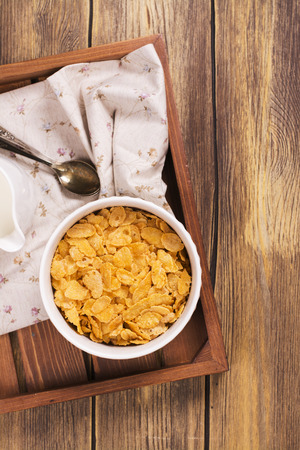Tasty and healthy breakfast on wooden tray. Female hand holding jar and adding milk into the bowl. Top view.の写真素材