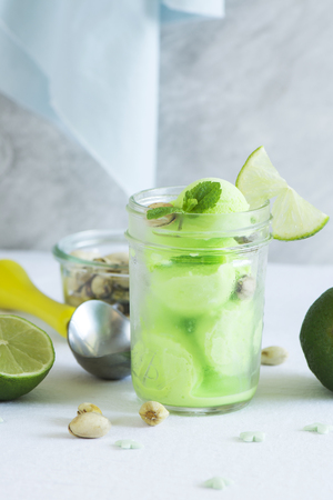 Homemade pistachio sorbet with lime, mint leaves and nuts in a glass jarの写真素材