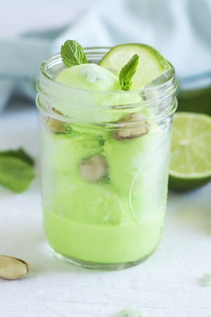 Homemade pistachio sorbet with lime, mint leaves and nuts in a glass jarの写真素材
