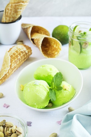 Homemade pistachio sorbet with lime, mint leaves, nuts and waffle cones. Selective focusの写真素材