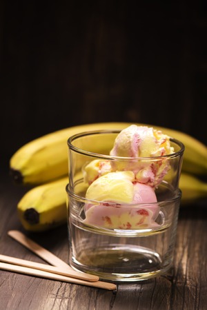 Homemade banana strawberry ice-cream in glasses over wooden backgroundの写真素材
