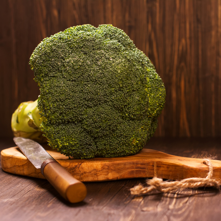 Fresh whole raw broccoli cabbage with vintage knife over grunge wooden table. Selective focusの写真素材