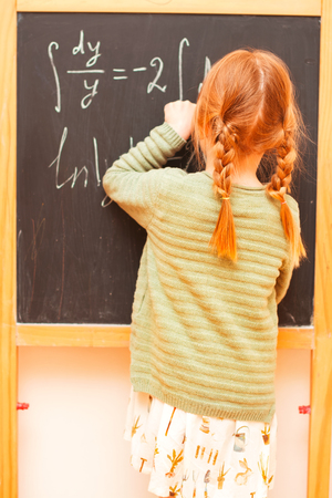 Back to school concept. Little girl writing formulas on blackboardの写真素材