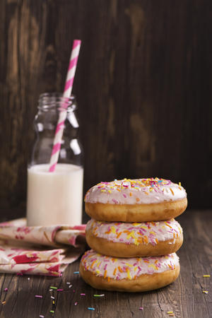 Homemade donuts and bottle of milk over wooden table. Vintage style. Selective focusの写真素材