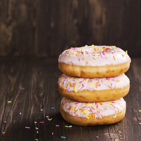 Pile of fresh homemade donuts with icing and colorful sprinklesの写真素材