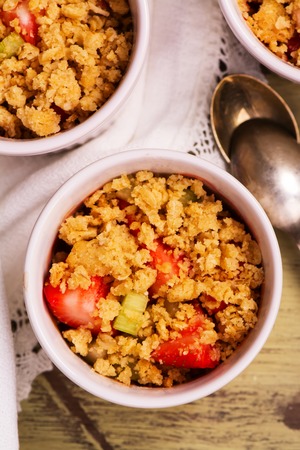 Crumble with strawberry, oat and rhubarb over wooden table. Top viewの写真素材