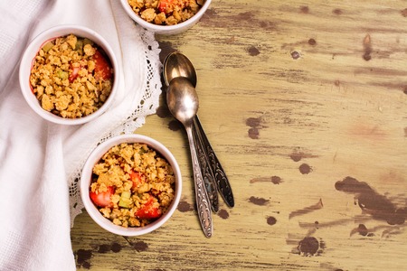 Crumble with strawberry, oat and rhubarb over wooden table. Top viewの写真素材
