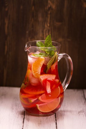 Jar of traditional red spanish sangria drink with different citrus over vintage wooden background. Selective focusの写真素材