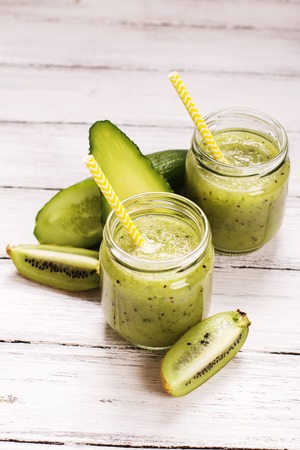 Green refreshing smoothie with kiwi, cucumber and apples over white wooden table. Selective focusの写真素材