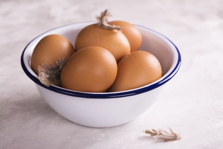Fresh eggs in an enamel bowl over stone tableの写真素材