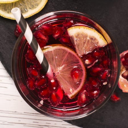 Pomegranate cocktail with lemon slices over wooden backgroundの写真素材