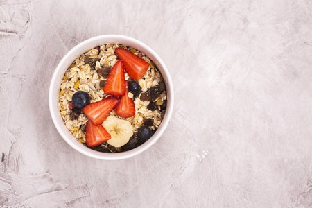 Homemade granola with fruits, berries and milk over stone background. Top view. Space for text