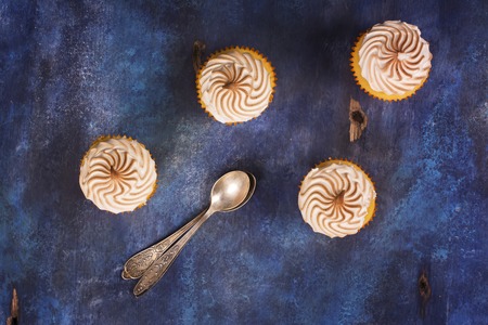 Lemon cupcakes with meringue and mint leaves over blue wooden table. Top viewの写真素材