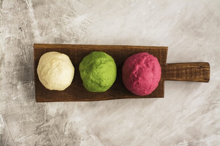 Colored balls of dough ready for baking. Burger buns with spinach, beet, sesame. Top view. Space for...